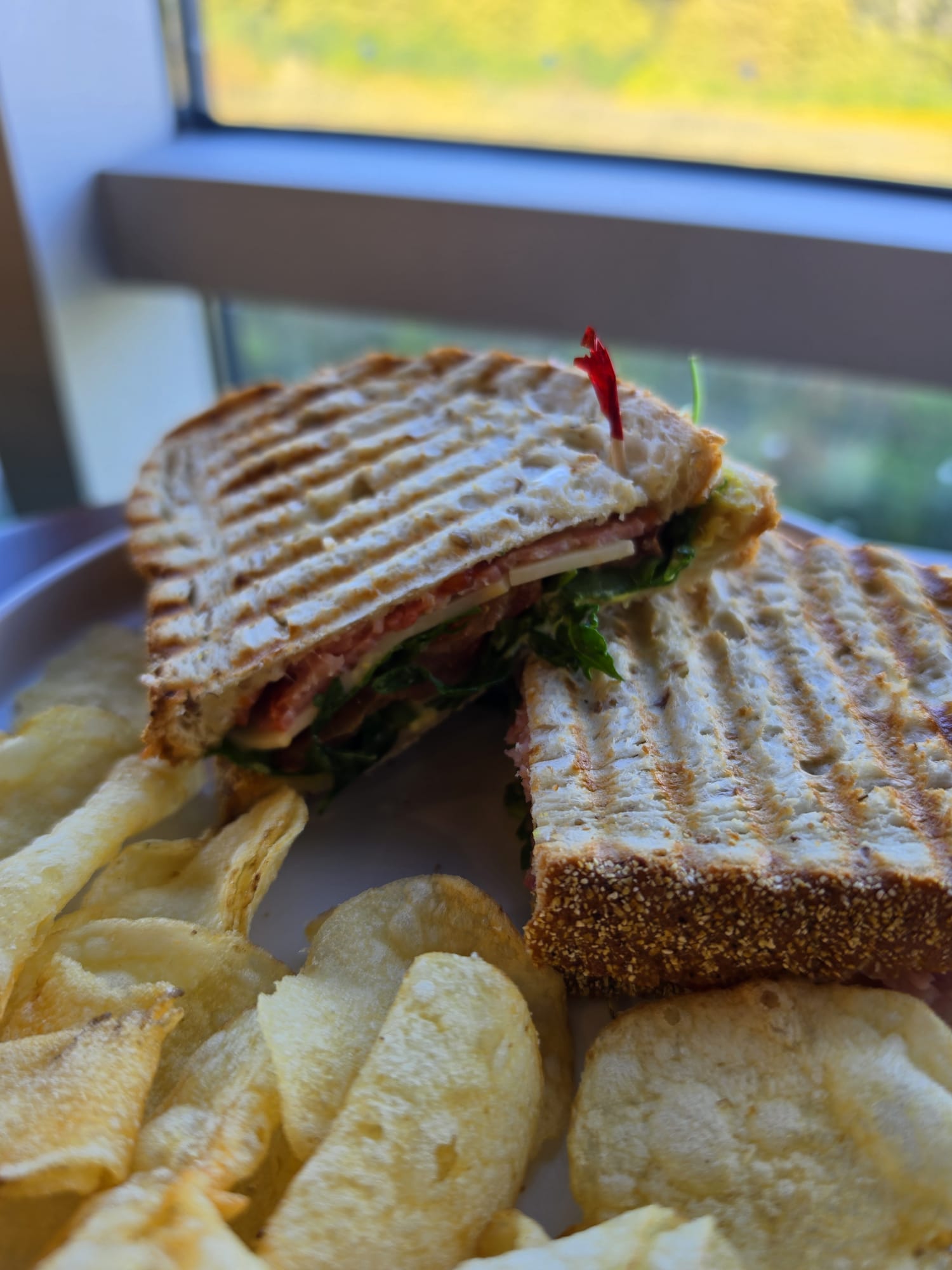 Grilled chicken pesto sandwich served with potato chips