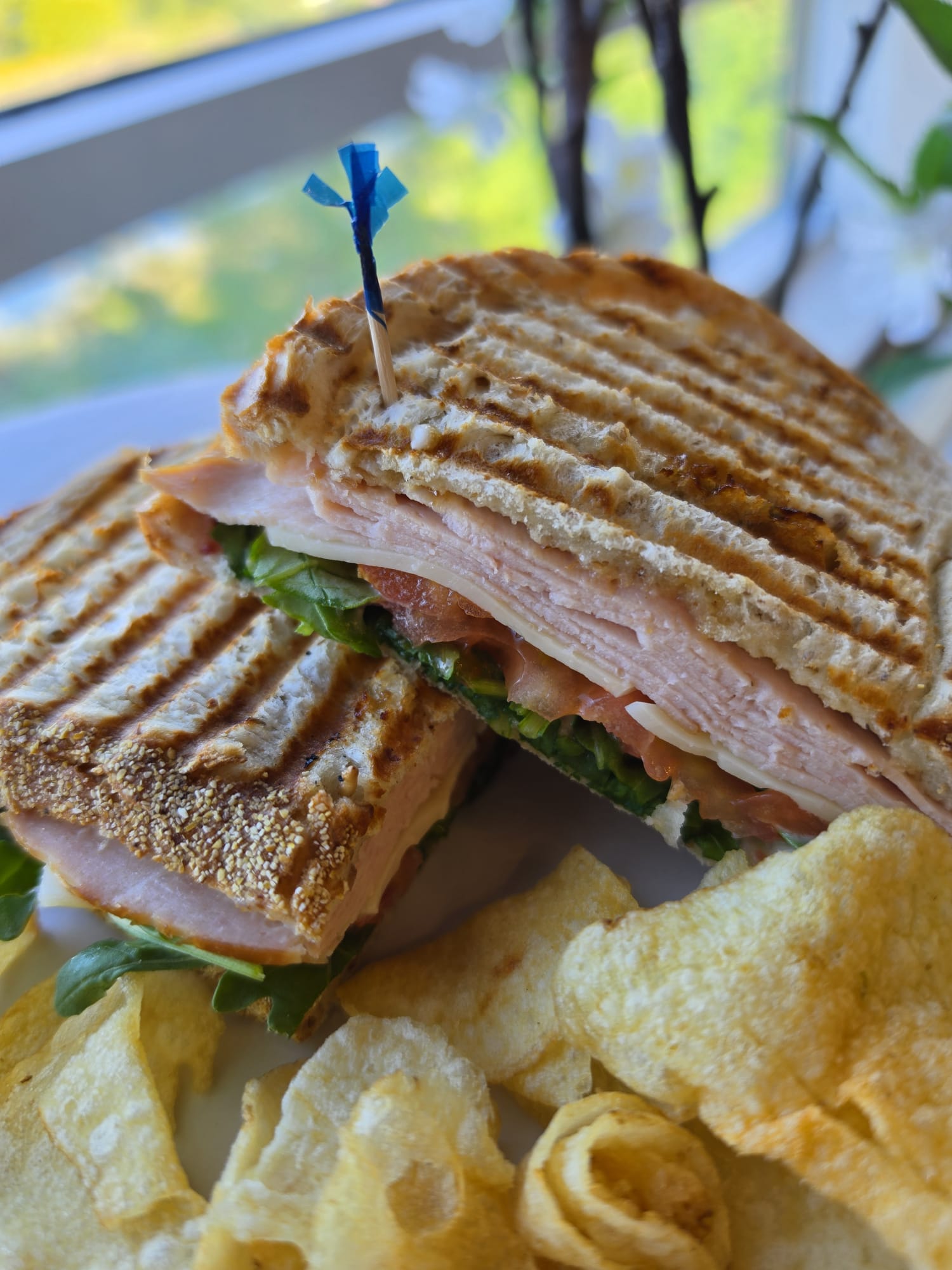 Grilled deli sandwich with greens and potato chips